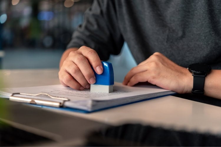 A man is stamping paperwork on a clipboard.
